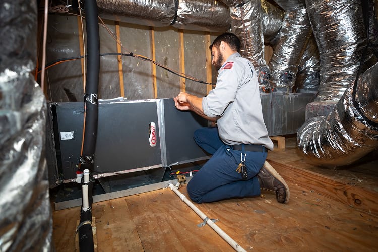 Mackey Services technician installing a furnace system in a Texas attic