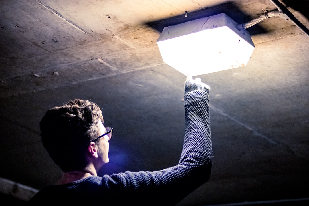 homeowner tightening a light bulb in a ceiling fixture safely