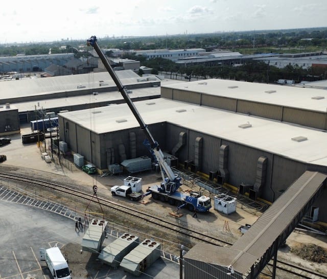 Crane lifting rooftop HVAC equipment at a commercial building site