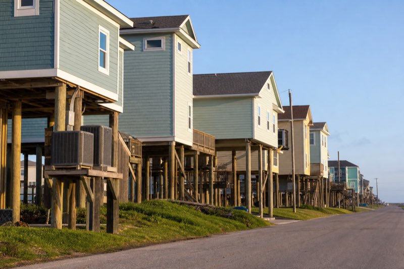 Row of elevated Gulf Coast beach houses on stilts with platform-mounted AC condensers