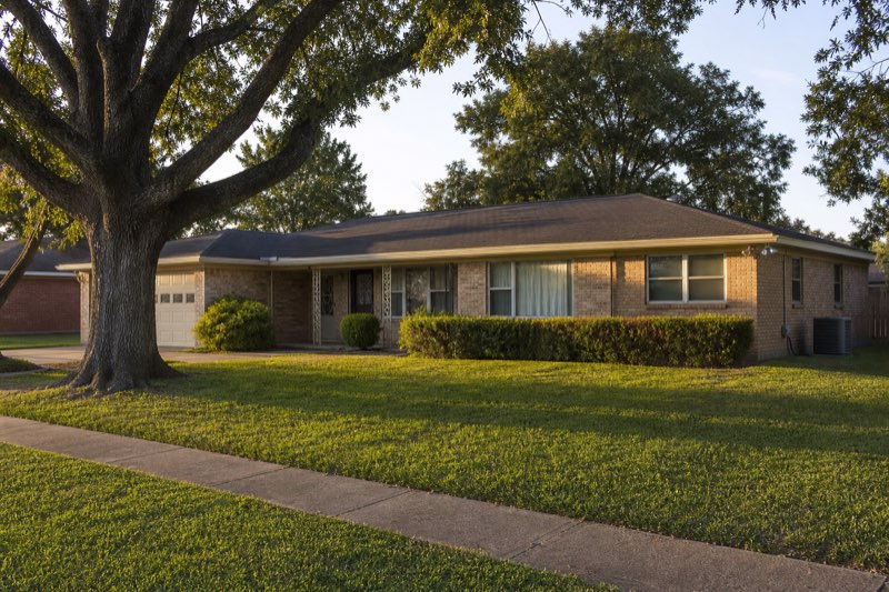 Classic 1960s single-story brick ranch home with side-yard AC condenser