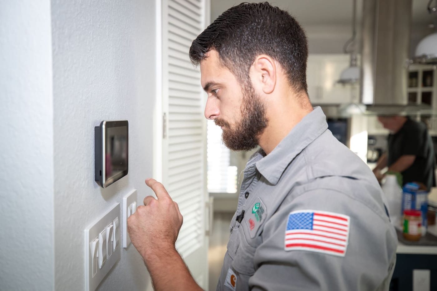 Mackey Services technician adjusting a smart thermostat in a customer's kitchen